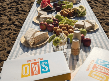 Picnic en la arena con medialunas SAO, fruta y sándwiches de miga